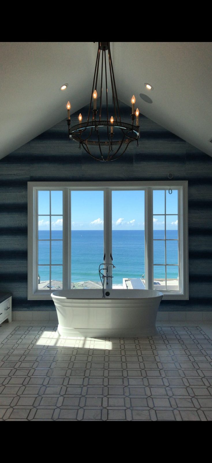 Bathroom with freestanding tub, ocean view, and textured blue wall finish