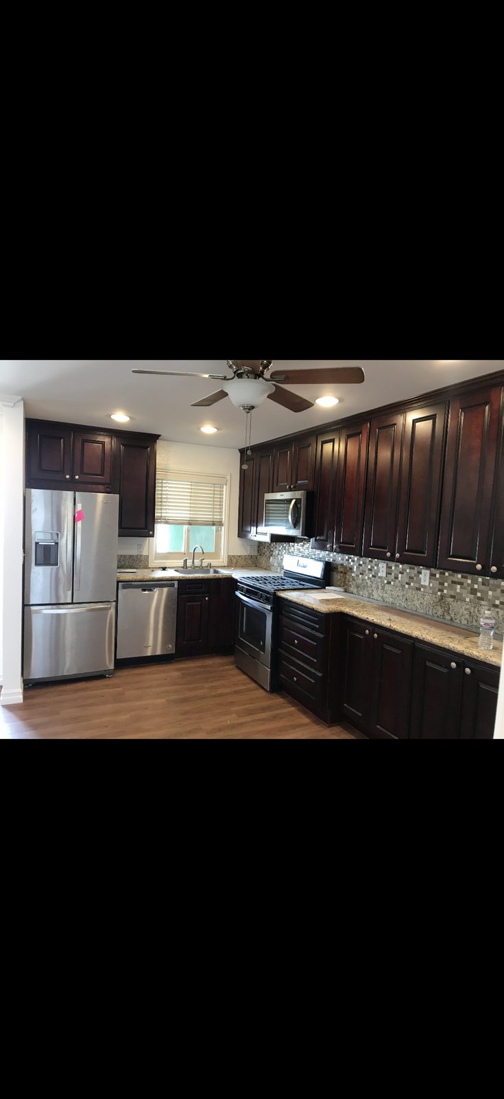 Kitchen with dark stained cabinets, granite counters, and stainless appliances