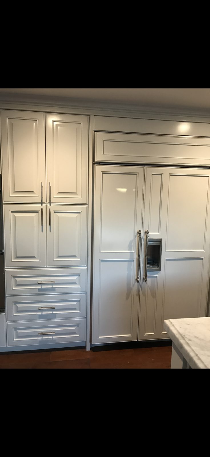 Kitchen cabinetry painted light gray with built-in panel refrigerator