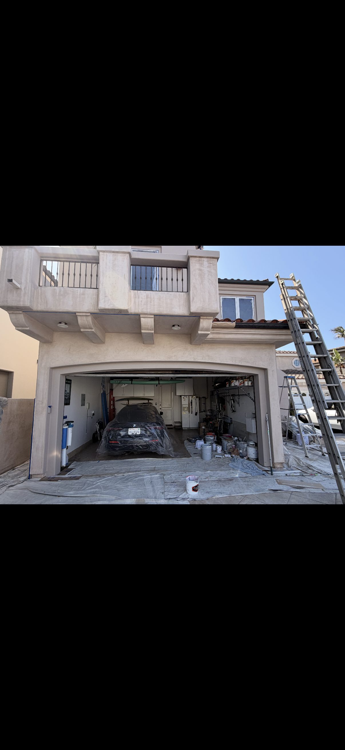 Mediterranean stucco exterior before painting with drop cloths and ladder